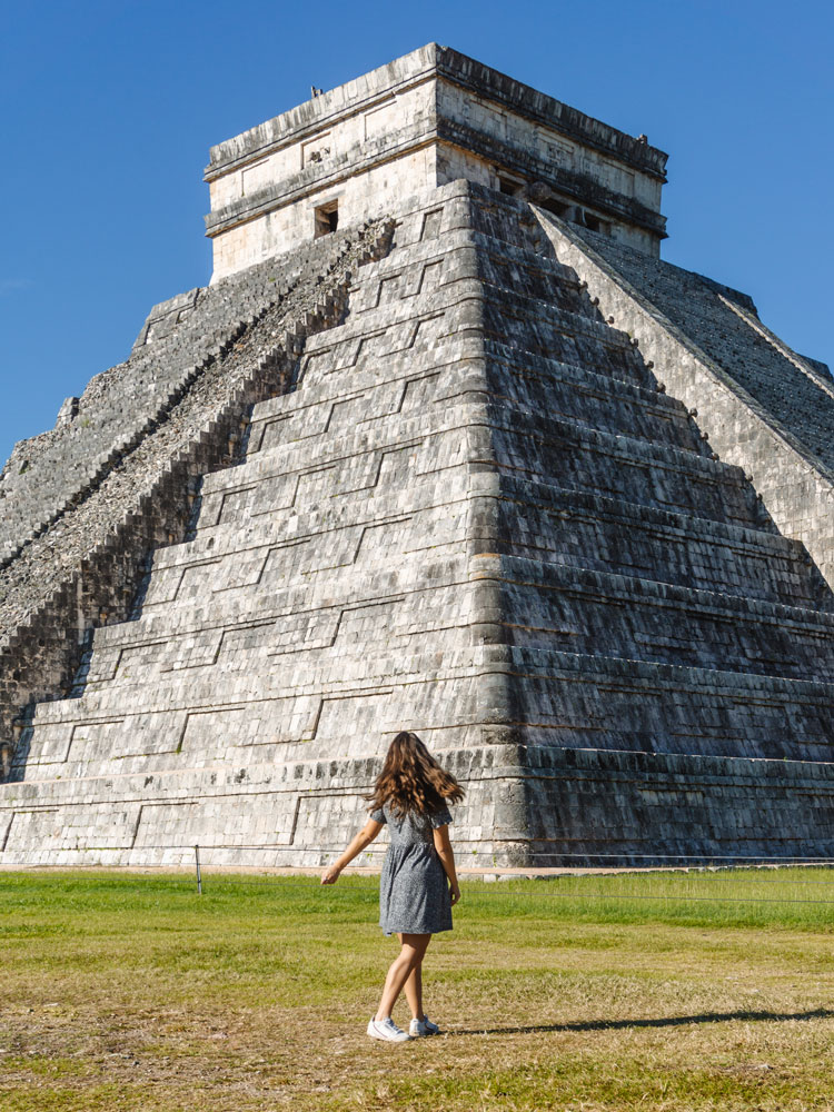 Woman in dress spinning in front of El Castillo at Chichen Itza in Mexico
